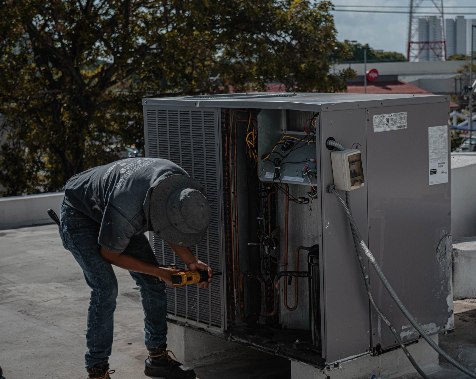 Technician working inside the open panel of an outdoor air conditioner